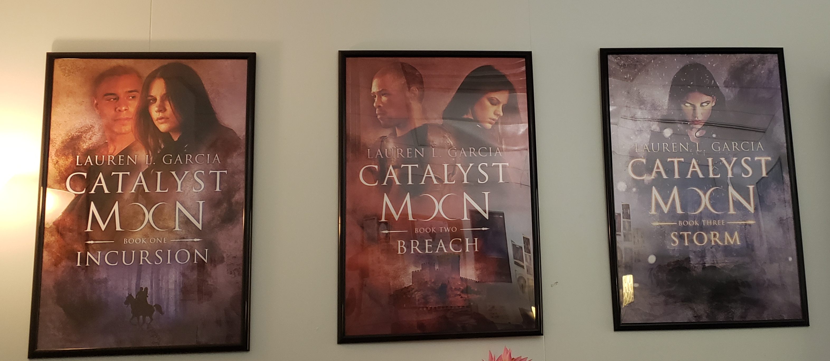 Picture of all three Catalyst Moon book covers on a wall in the author's office.